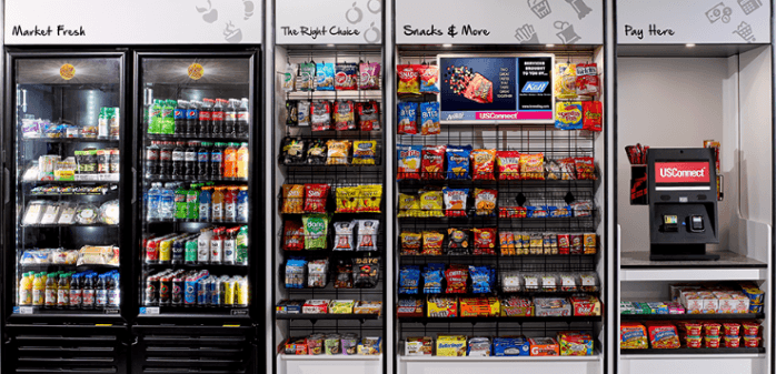 A Beard Bros micro market with coolers, open-air snack shelving, and a self-checkout kiosk